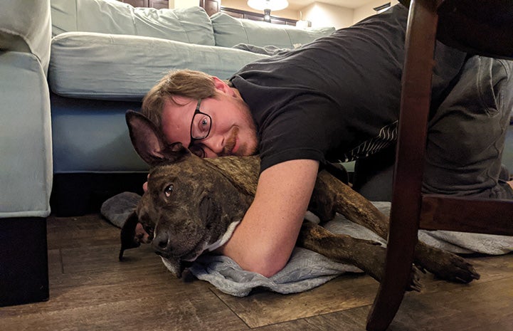 Person snuggling with Bonnie the dog in front of a couch