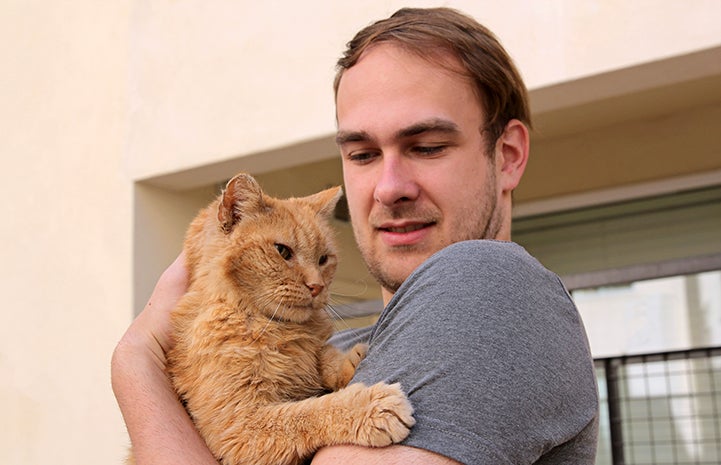 John holding Lionel the senior orange tabby cat