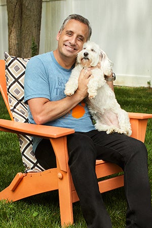 Joe Gatto sitting in a chair and holding a small white dog