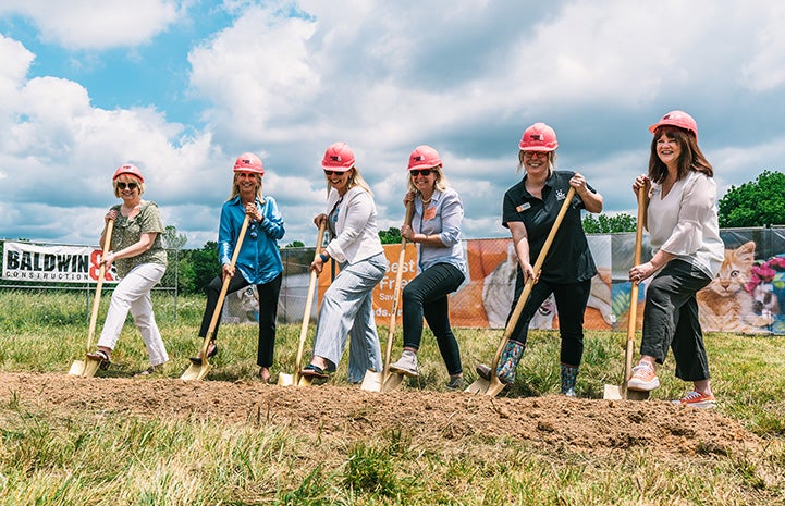 Six people wearing hardhats and holding shovels for the ceremonial groundbreaking for the Best Friends Pet Resource Center in Northwest Arkansas