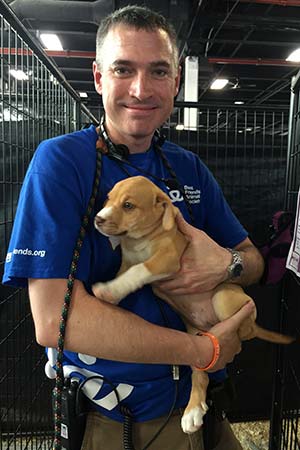 Volunteer Dale Musselman holding a puppy at an adoption event