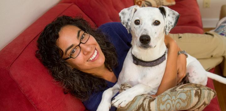 Woman and her white-and-black foster dog on red couch