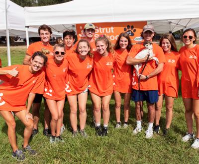 Group of Best Friends volunteers at an offsite event, wearing orange T-shirts and holding a dog