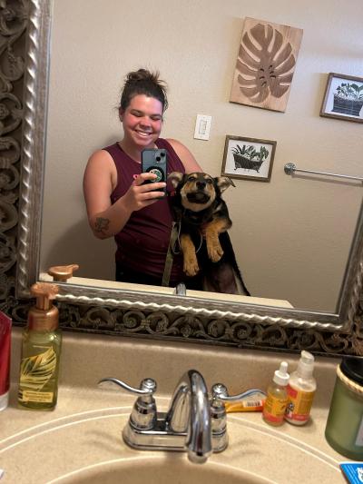 Person smiling and taking a mirror selfie with Jalapeño the dog