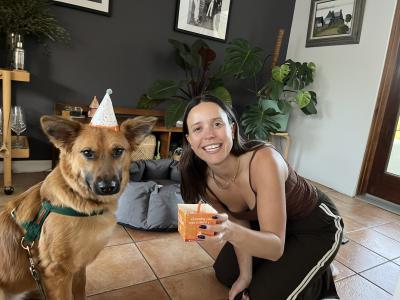 Hadley holding the adoption cake next to Kimchi the dog, who is wearing her adoption hat