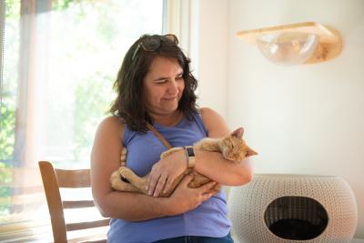 Person cradling an orange tabby cat in her arms