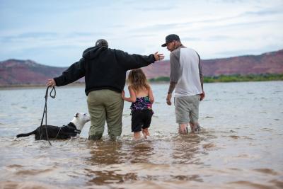 Rosita the dog with her new family having fun in some water with red cliffs behind them