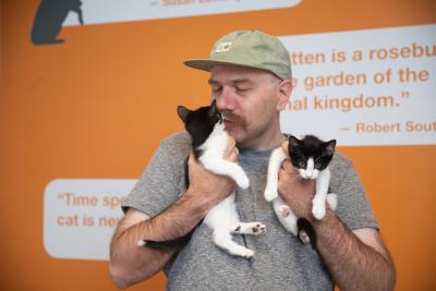 Foster Tyler Lisonbee holding two black and white kittens and kissing one of them