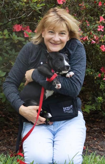 Volunteer Lisa cradling a black and white puppy in her arms