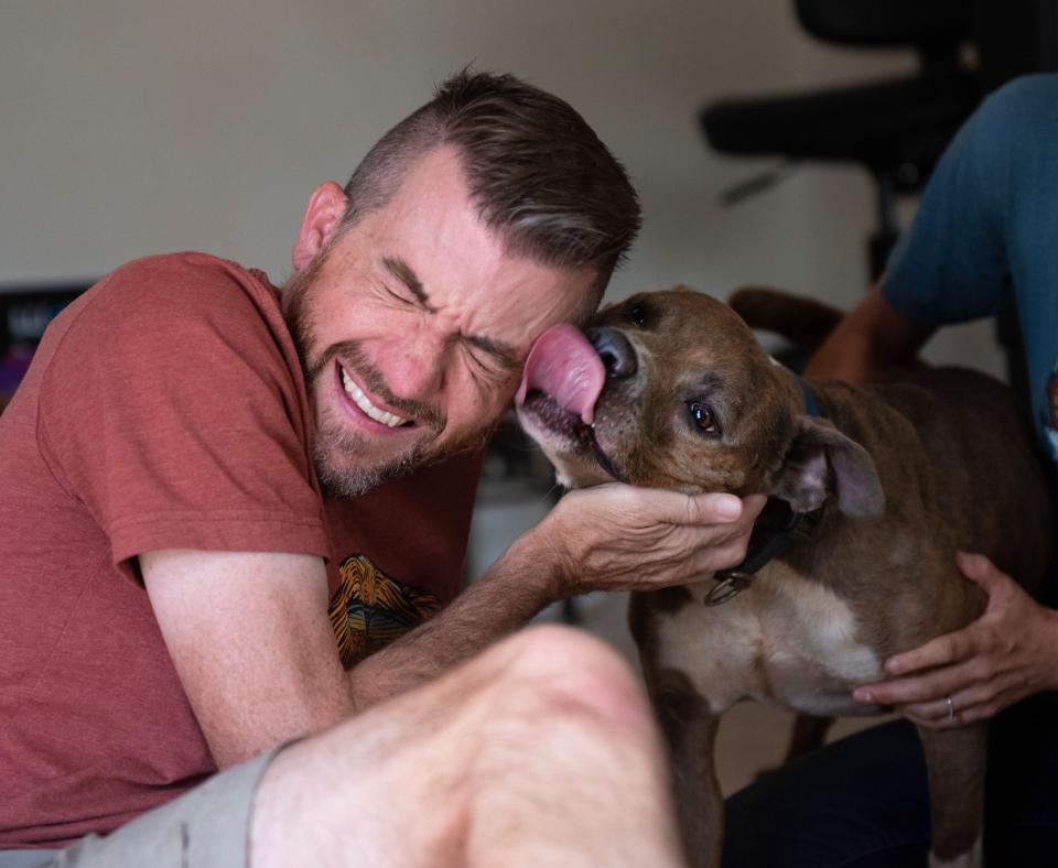 Man smiling and laughing as a dog kisses his face
