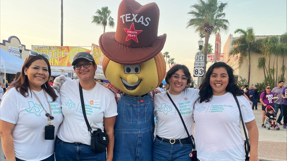 Ira and Vanni with two other people and a mascot wearing a cowboy hat with the word "Texas"