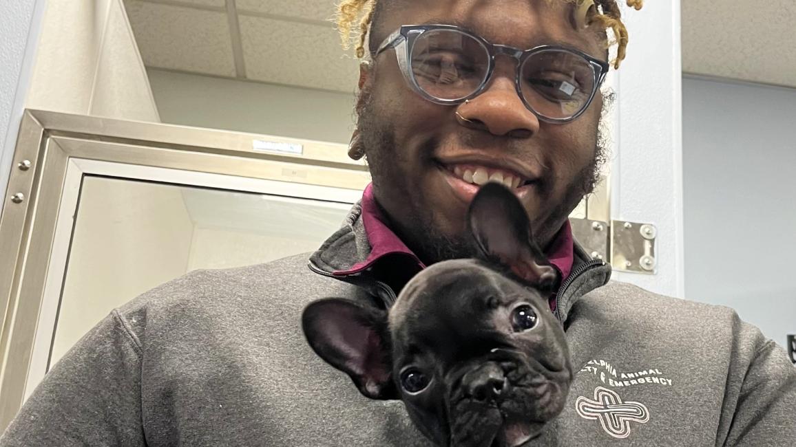 Jordan Powell  holding a black French bulldog puppy in his shirt