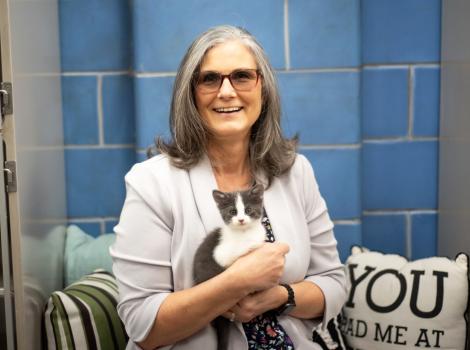 Smiling woman holding a gray and white kitten
