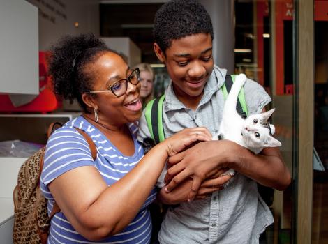 Two people smiling and holding a white and gray kitten