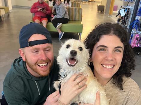 Happy couple holding a small white dog they'd adopted