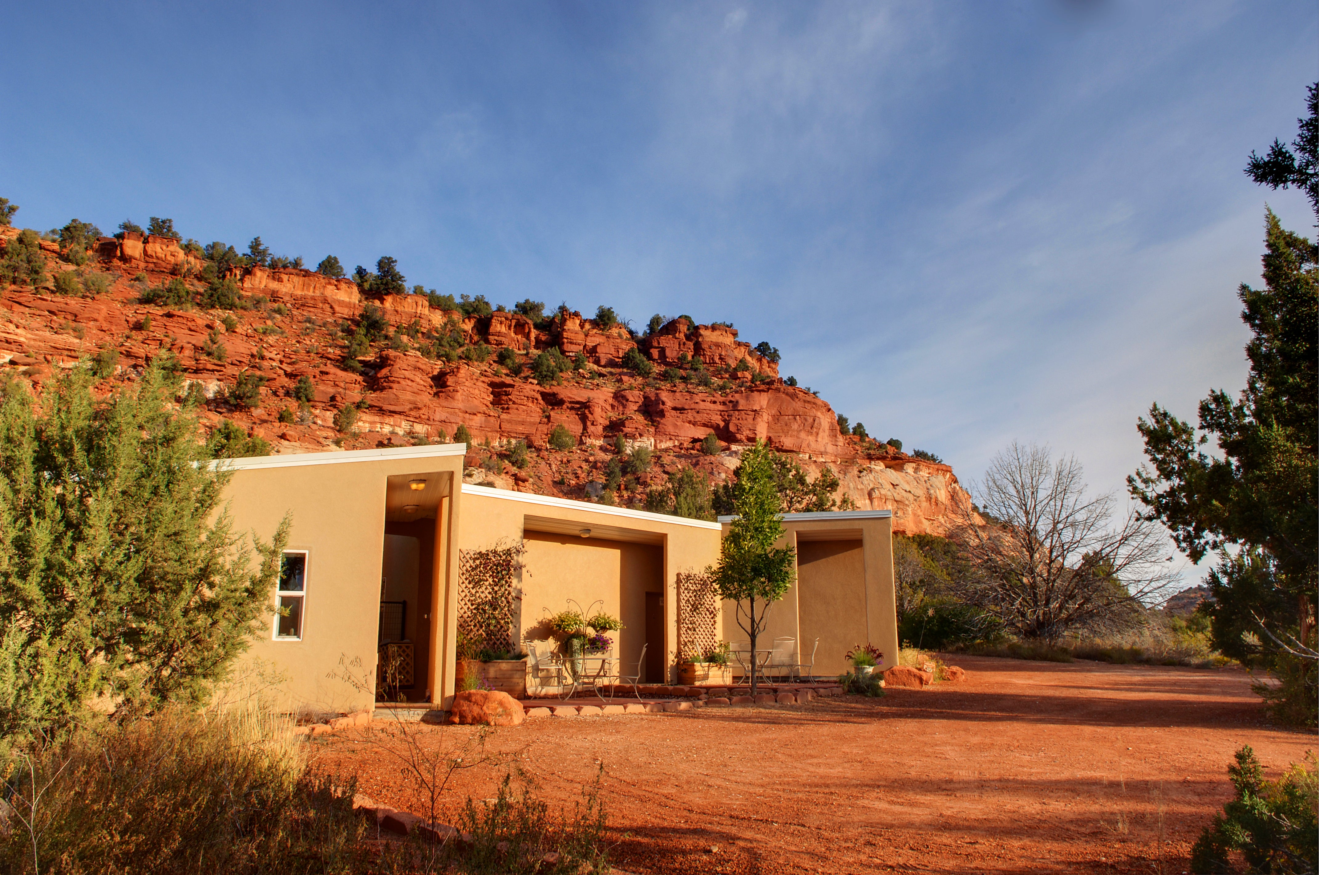 Small tan building with a backdrop of red rock cliffs and blue sky