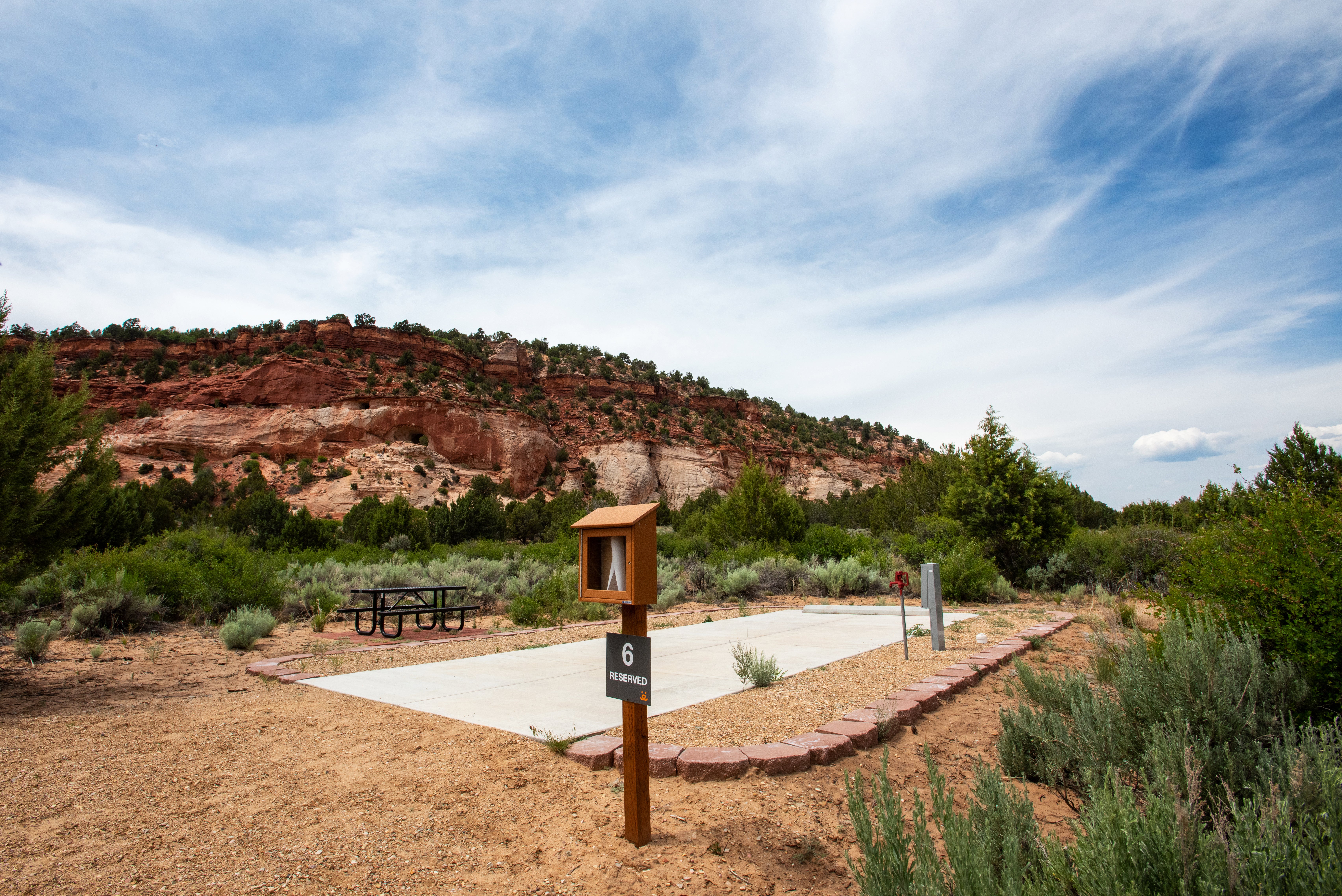 RV site with a backdrop of red rock cliffs and blue sky