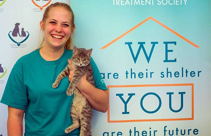 Woman from the Humane Animal Treatment Society holding a gray tabby kitten