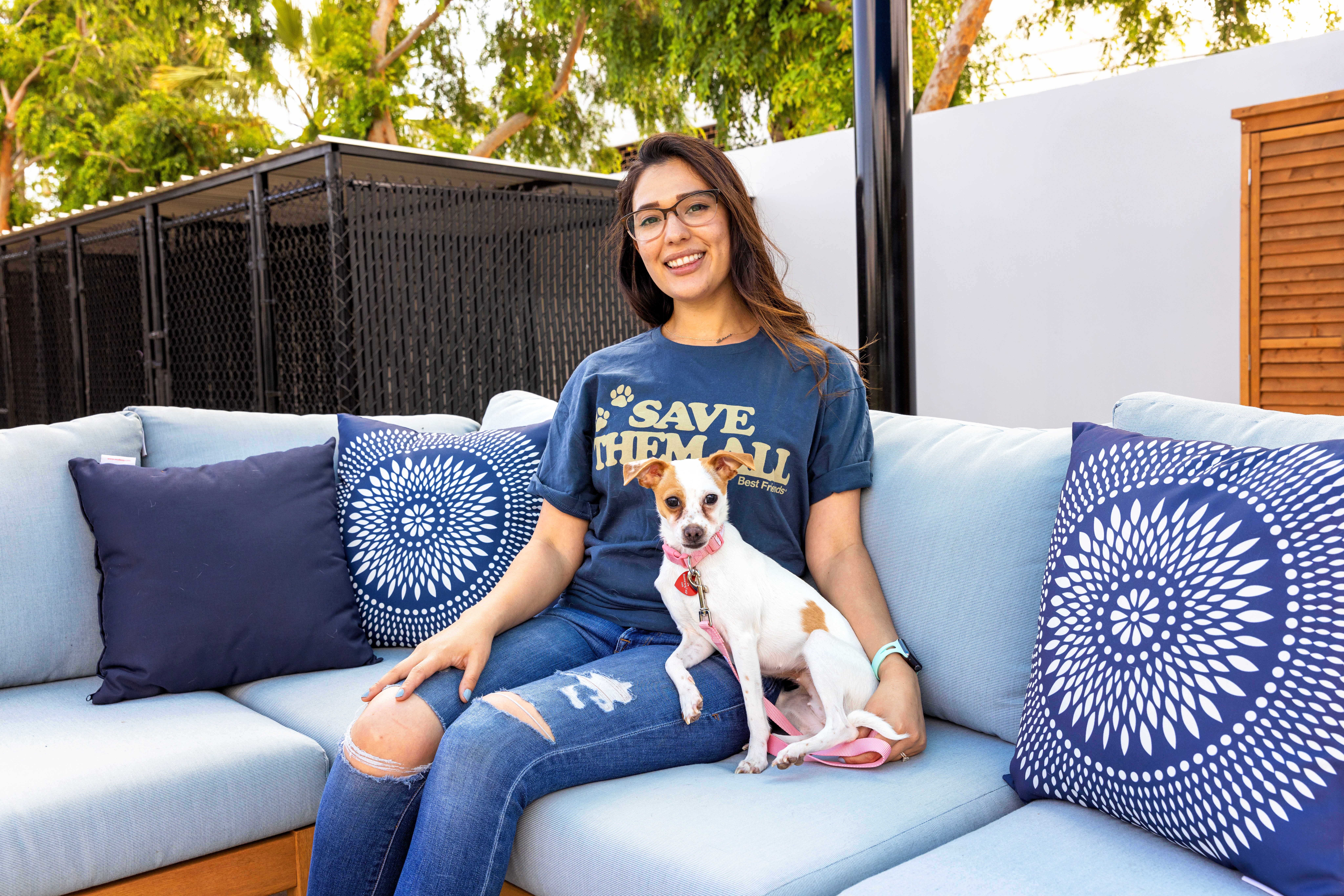 Smiling person wearing a Best Friends shirt on an outdoor couch with a dog