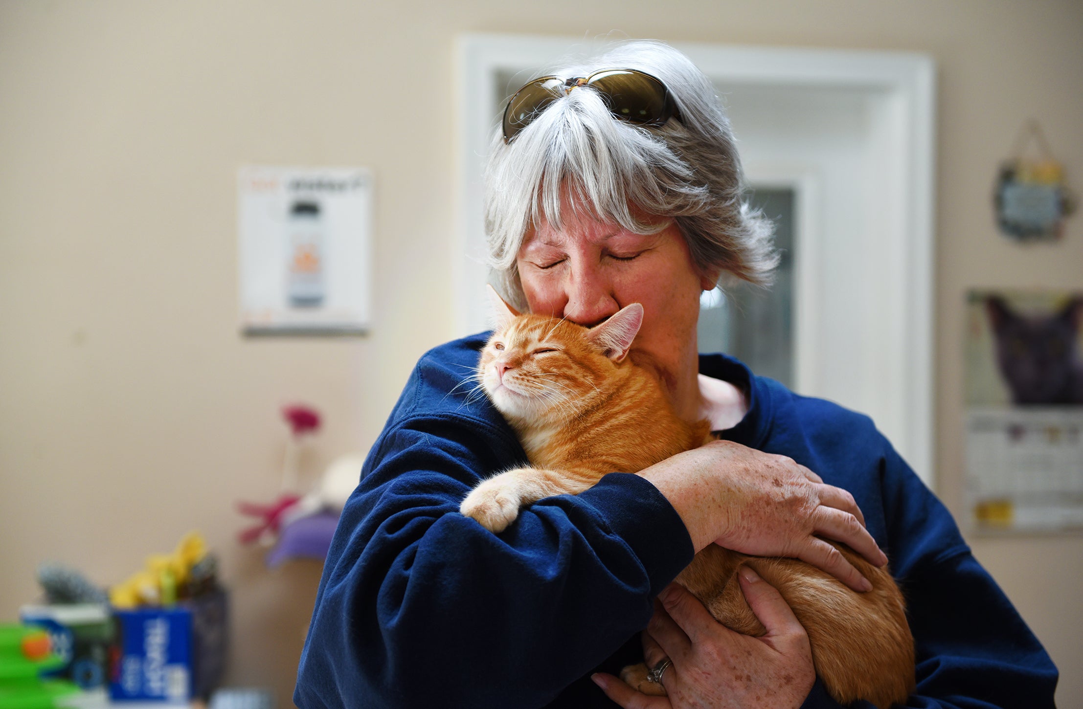 Woman holding and hugging an orange tabby cat
