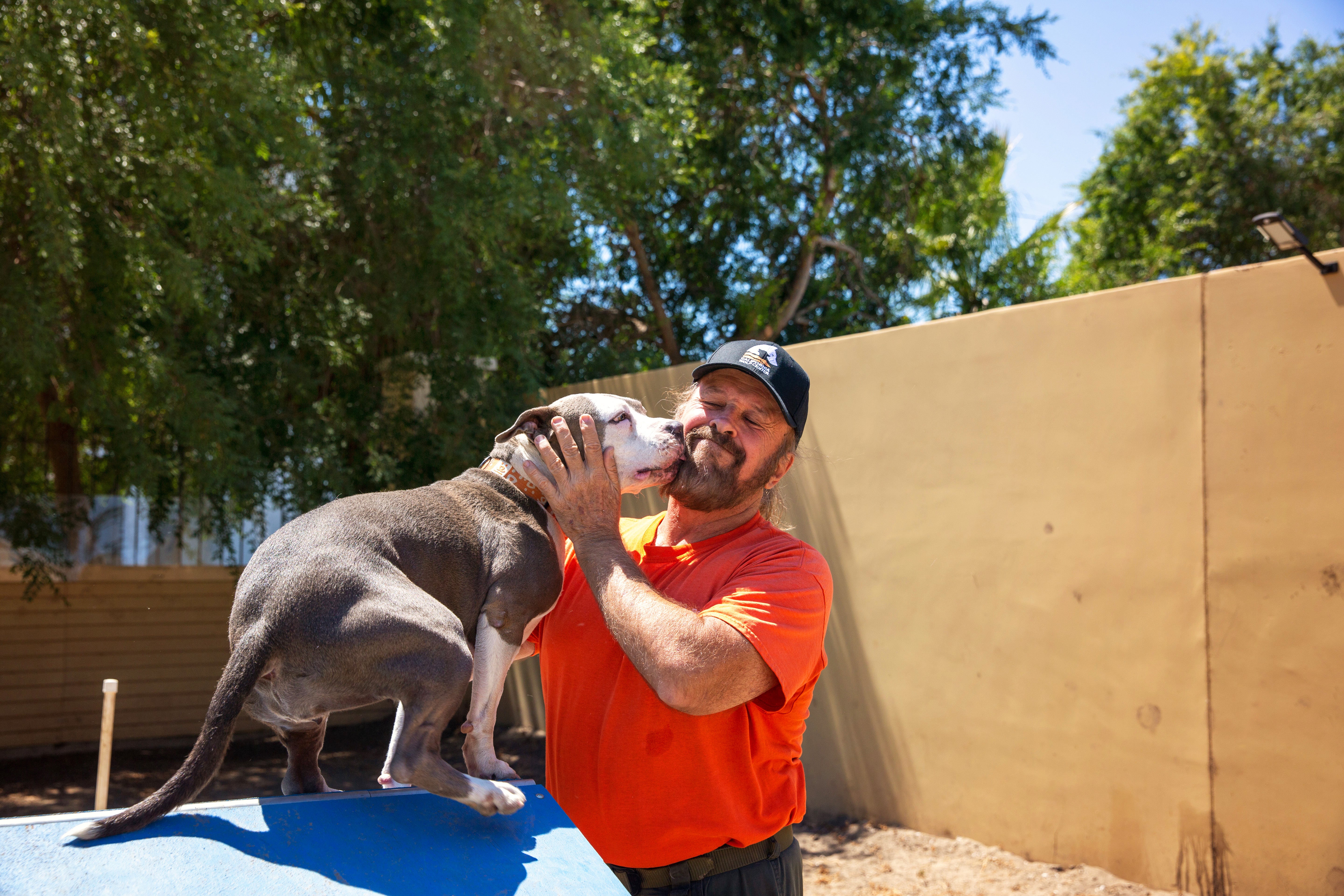 Dog kissing the face of a volunteer wearing a Best Friends orange T-shirt