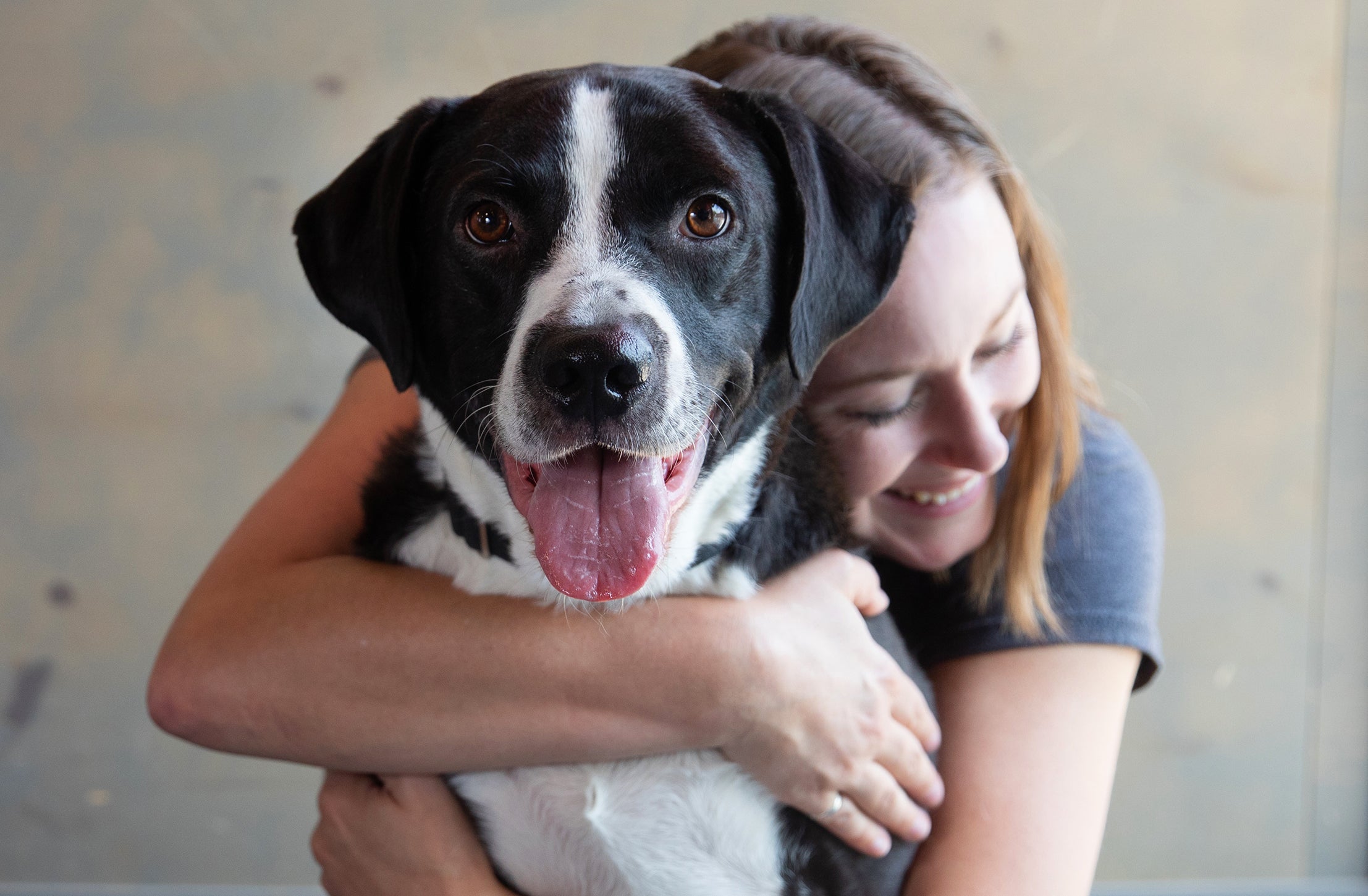 Smiling person hugging a black and white dog