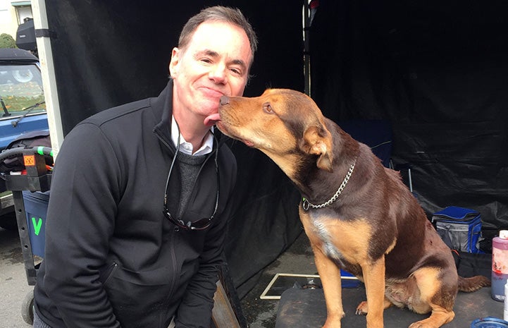 Bruce on the set of A Dog's Way Home getting a kiss from Shelby the dog