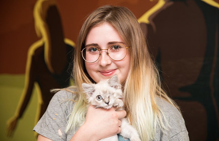 Woman holding a little one-eyed Siamese kitten who she adopted