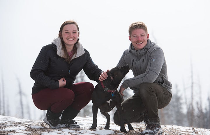 Dakota the dog outside in the snow with two people on either side of her