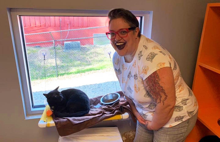 Woman with wide smile with the cat she's adopting in a window