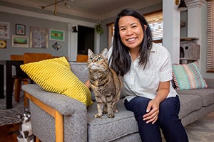 Angela Li sitting on a couch with two cats