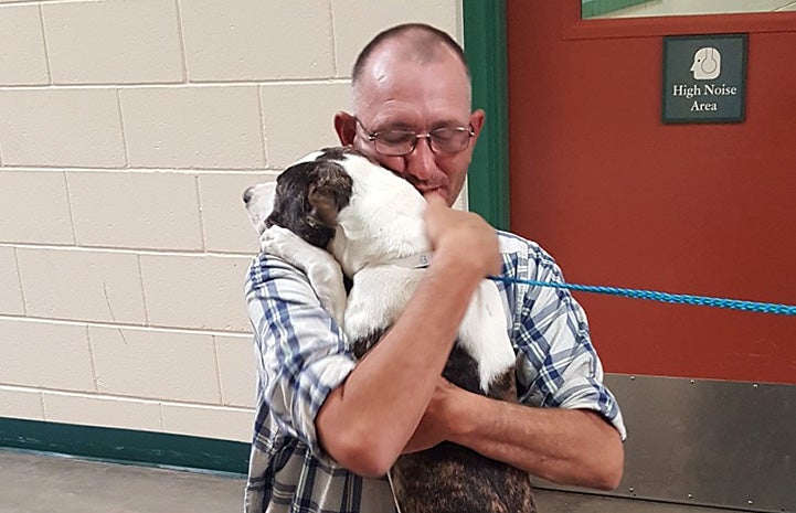 Man being reunited with his missing dog and giving him a hug