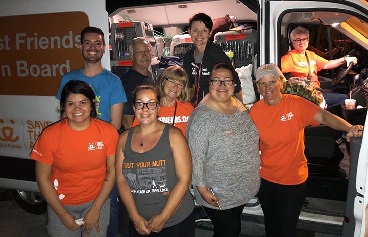 Group of people standing in front of a transport van with a woman wearing a Best Friends T-shirt in the driver's seat