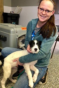 Smiling woman holding a fluffy black and white puppy on her lap