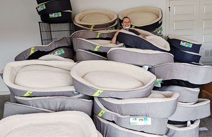Woman standing in the middle of a huge pile of dog beds donated from Petco
