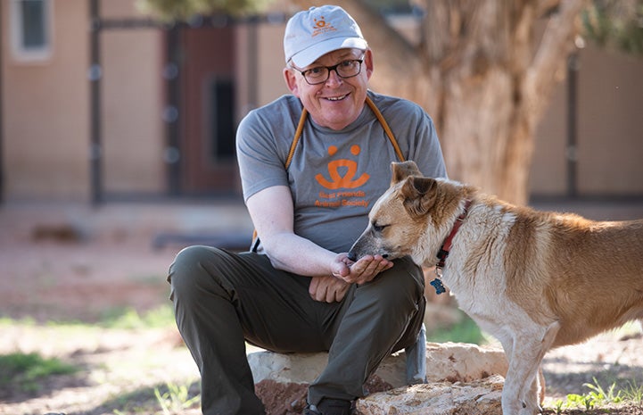 Fred, a volunteer at Best Friends Animal Sanctuary, feeding a treat to Skelly a dog in Dogtown