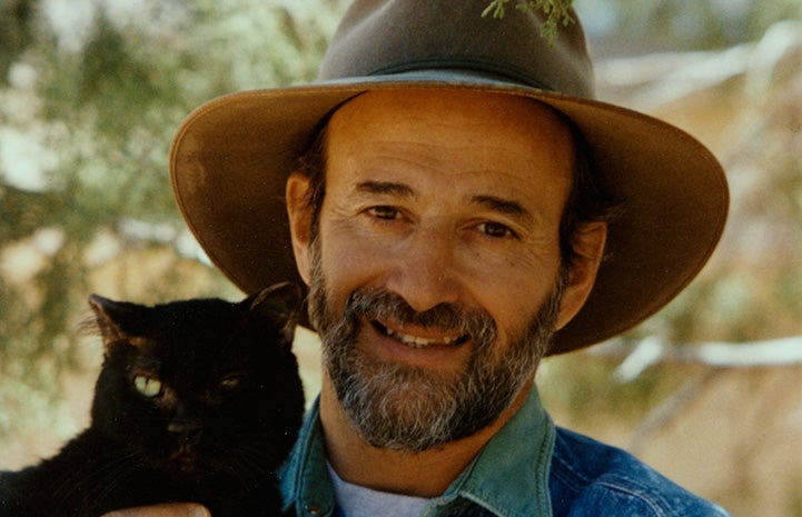  Francis Battista wearing a wide brimmed hat and holding Blackjack the cat