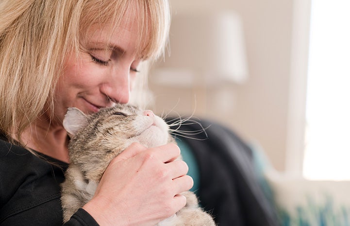 Smiling woman holding Mr. Henry Cheeks the cat with big jowls