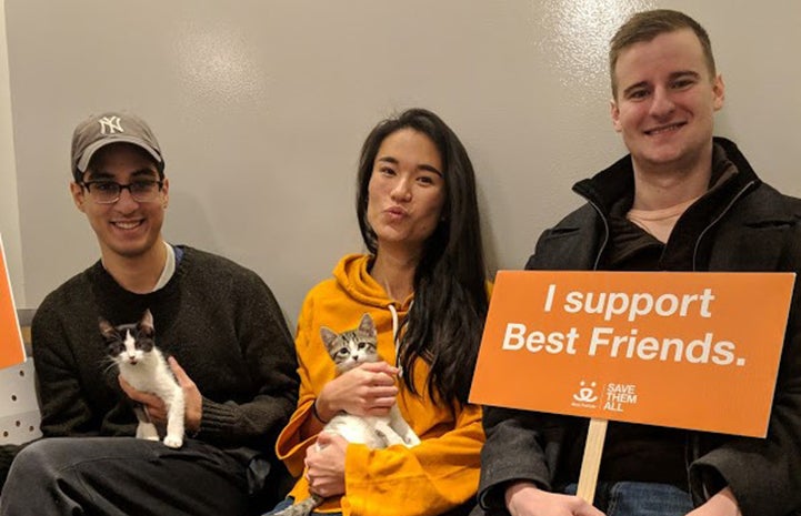 Three people holding two kittens they'd just adopted and a sign stating, I Supper Best Friends