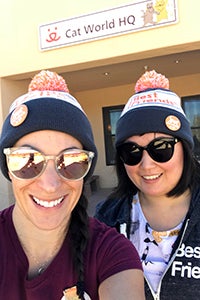 Volunteers Natalie Pascale and Deborah Hur wearing Best Friends hats, posing in front of Cat World HQ