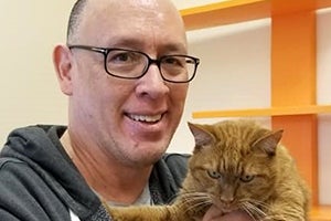 David Tow holding Hobbes the orange tabby cat