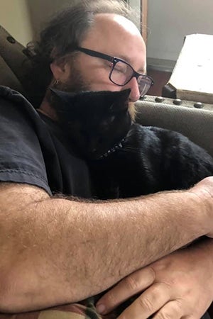 Daniel Miller lying down and hugging Jordan the cat