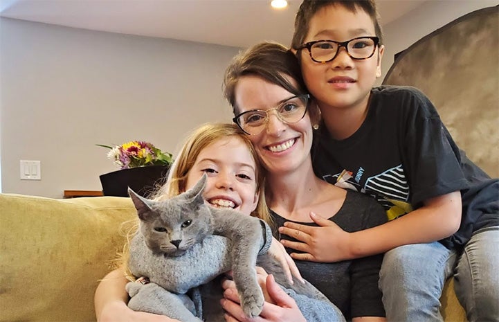 The Sano family sitting on a couch together and posing with their newly adopted gray cat