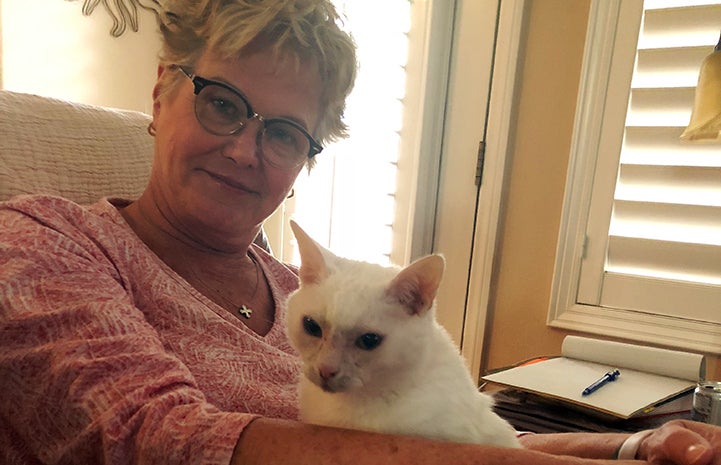 Adopter Dianne Beckman holding white cat Sonya on her lap