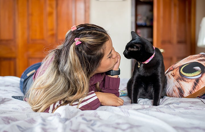 Vanessa Hernandez lying on the bed with Bella the black cat