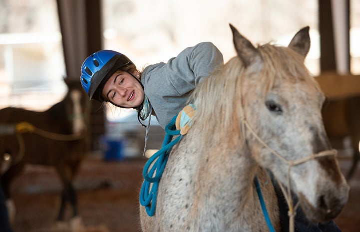 Woman getting up onto the back of a horse