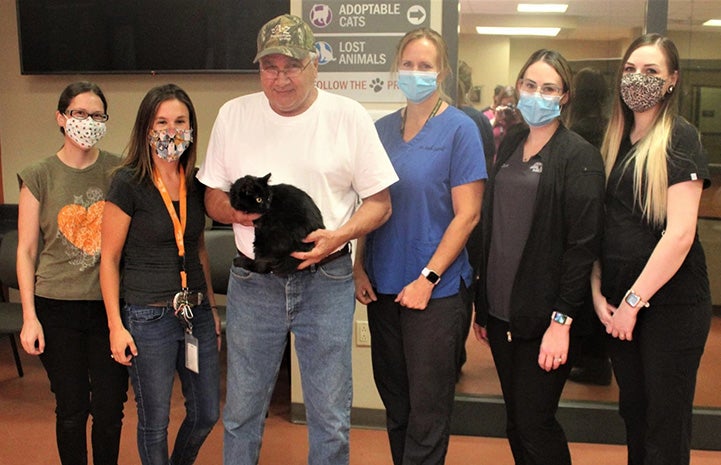 Stanislaus Animal Services Agency staff standing next to a man holding Miss Corona the cat