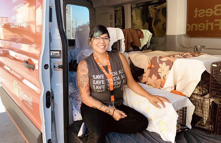 Woman wearing a Save Them All T-shirt in a van with a bunch of covered humane traps