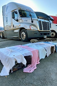 Row of humane traps covered in sheets lying in front of a truck