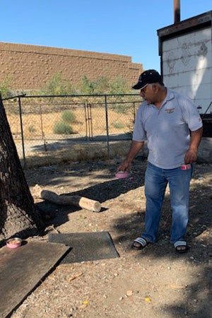 Malcolm setting out some food by a tree for community cats